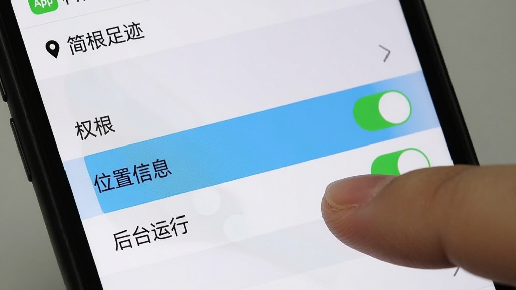 一张展示手机设置界面的图片,画面中手指正在点击“简足迹”App的权限管理选项,屏幕上高亮显示“位置信息”和“后台运行”两个权限开关,背景是手机系统设置菜单,风格写实,画质清晰,重点突出权限设置步骤