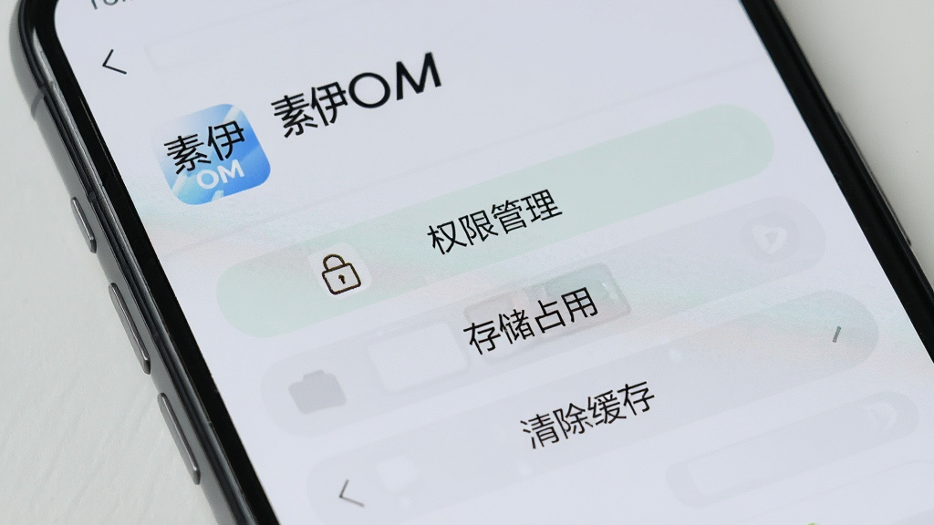 一张手机屏幕特写,画面显示“素伊OM”的应用信息页面,页面中有“权限管理”“存储占用”“清除缓存”等按钮,背景为浅灰色,风格干净整洁,画质清晰