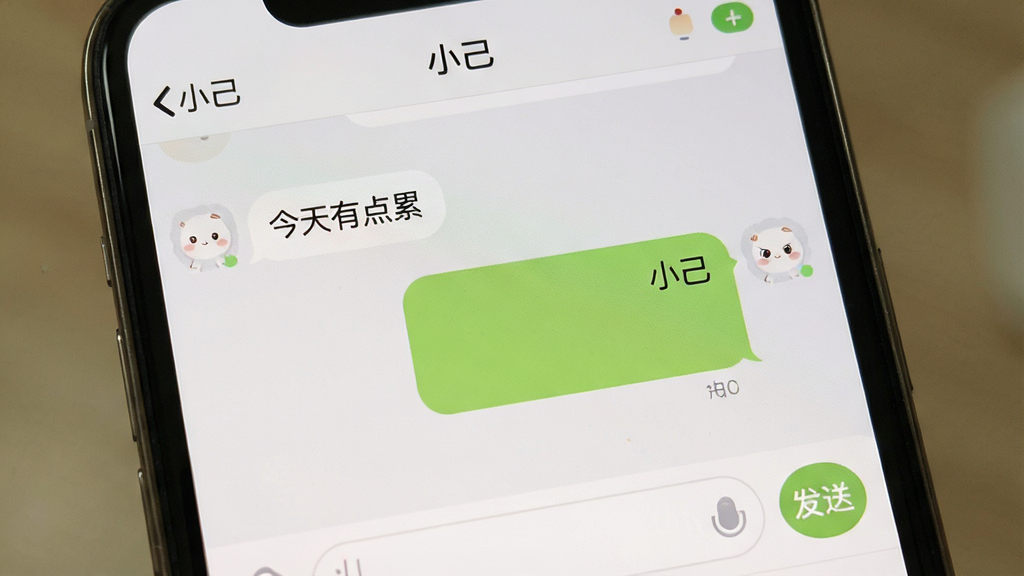一张手机屏幕特写图,画面展示“小己”应用的对话界面,屏幕中央是聊天气泡,左侧是用户发送的文字“今天有点累”,右侧是“小己”的回复气泡,背景为浅灰色,界面顶部显示“小己”名称和在线状态,底部为输入框和发送按钮,整体风格简洁温和,画质干净,无多余元素