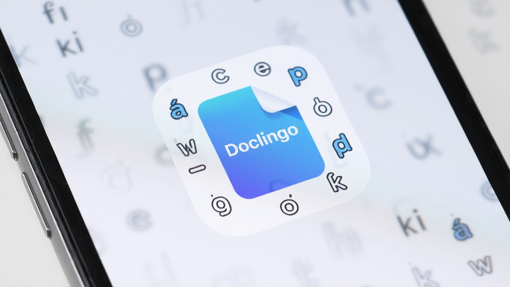 һ���ֻ���Ļ��������д����Ļ������ʾ��Doclingo��Ӧ��ͼ�꣬ͼ�����Ϊ���׽�����ĵ���ʽ����Χ�����Ŷ�������ĸ���ţ�����Ϊ������ǳ��ɫ������ɾ�������ͻ��������רҵ���ࡣ