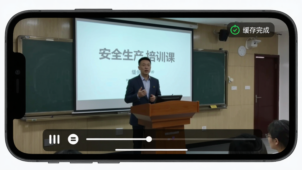 生图提示词:手机横屏播放视频的画面,视频内容是一堂关于安全生产的培训课,画面中讲师站在讲台前,身后是投影幕布,视频播放器下方有播放/暂停按钮和进度条,右上角有“缓存完成”的绿色小图标,手机屏幕外框是深灰色,画质干净无多余元素。