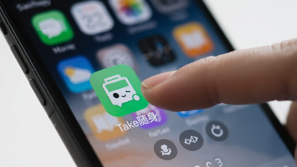 一张手机操作场景图,画面中手指正在点击手机屏幕上的“Take随身”应用图标,手机背景虚化,突出主体,风格写实,细节清晰,画质干净无多余元素。