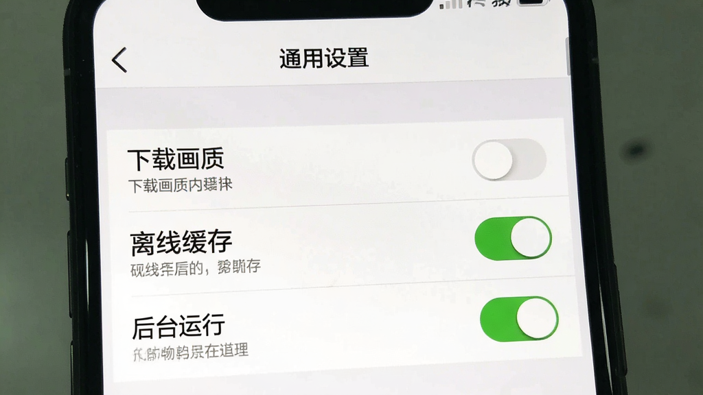 一张展示“健身有宝”设置界面的图片,主体为手机屏幕内显示“通用设置”页面,包含“下载画质”、“离线缓存”、“后台运行”等多个选项开关,其中“后台运行”已开启,界面为白色背景黑色文字,选项下方有灰色小字说明,整体布局清晰,风格简洁实用,画质干净无多余元素
