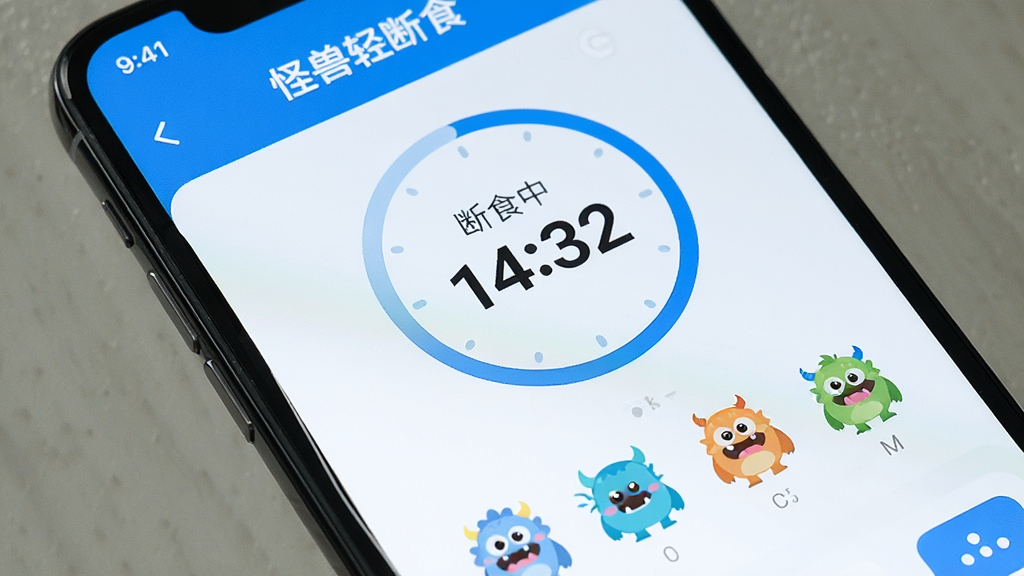 һ���ֻ���Ļ��д����Ļ����ʾ���������ʳ��APP�������棬��������һ��Բ�εĶ�ʳ��ʱ������ʾ����ʳ�� 14:32������ʱ���·��м����ɰ���С����ͼ�꣬����UI��������£�������Ϊ��ɫ�������ʸɾ��޶���Ԫ�ء�