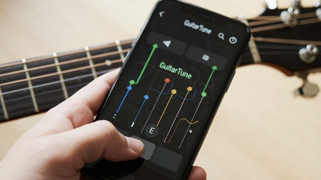 һֻ�������ֻ�����Ļ��ʾ��GuitarTune���ĵ������棬Ĵָ��׼�������Ļ�·��ġ�E���Ұ�ť��������ģ���ļ����پ������ң�����ǿ����ָ����Ļ�Ľ�����������Ȼ����ͼ���գ����������޶���Ԫ��