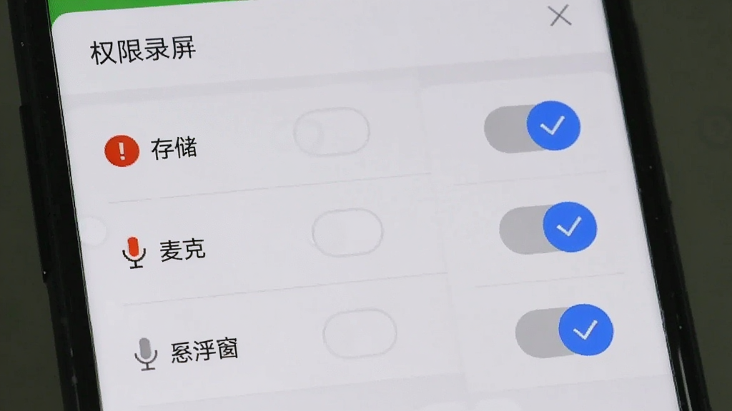 手机屏幕显示EV录屏的权限设置界面,有存储、麦克风、悬浮窗三个权限开关,旁边有红色感叹号和蓝色对勾图标,背景是手机设置菜单,风格简洁,图中包含文字