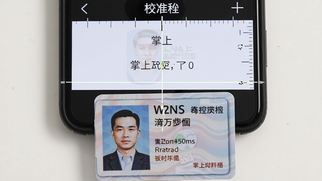 手机屏幕显示掌上尺子的校准界面,画面中有一张身份证贴在屏幕下方,屏幕上有对齐提示线和文字说明,主体是手机和身份证,布局为俯视特写,排版简洁,风格教程示意,细节包含校准线和身份证边缘,画质清晰,干净,无多余元素