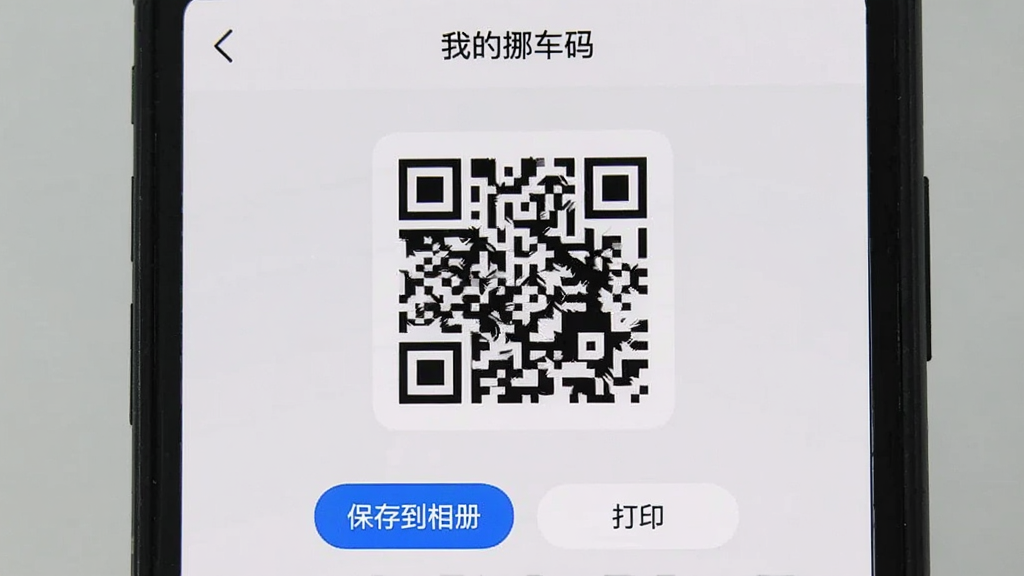 手机屏幕显示“一键挪车码”App的二维码生成页面,页面中央是一个大尺寸二维码,下方有“保存到相册”和“打印”两个按钮,顶部有“我的挪车码”标题,背景是浅灰色,风格简约,细节清晰,画质干净,无多余元素